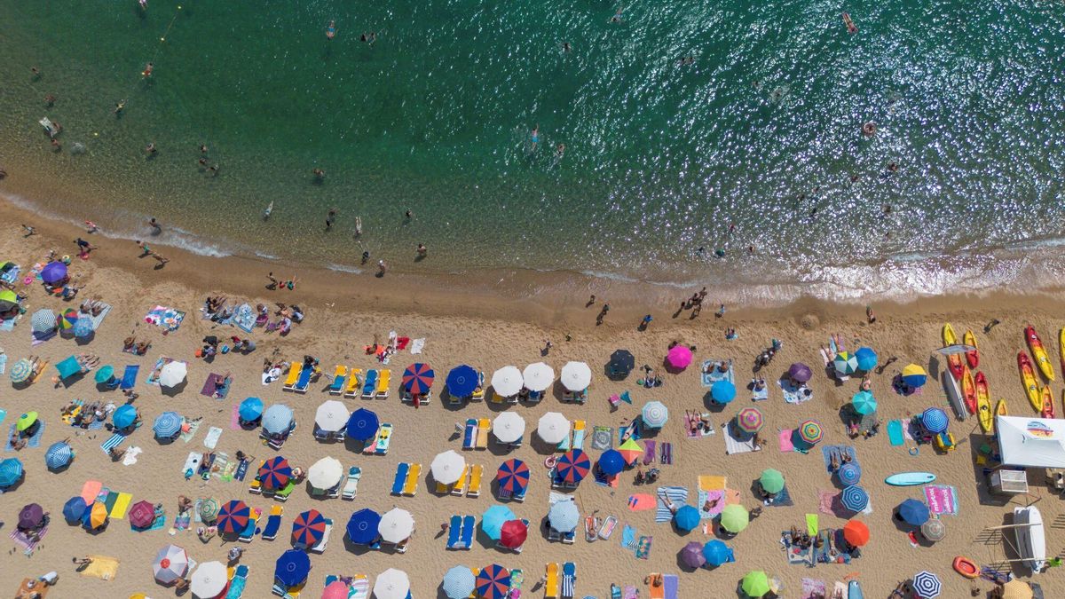 Numerosas personas disfrutan de un día de playa .