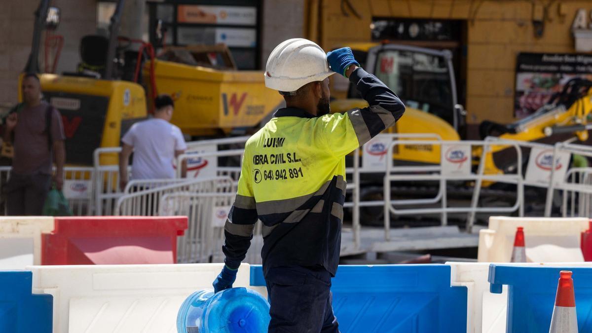 Un trabajador transporta un bidón de agua.