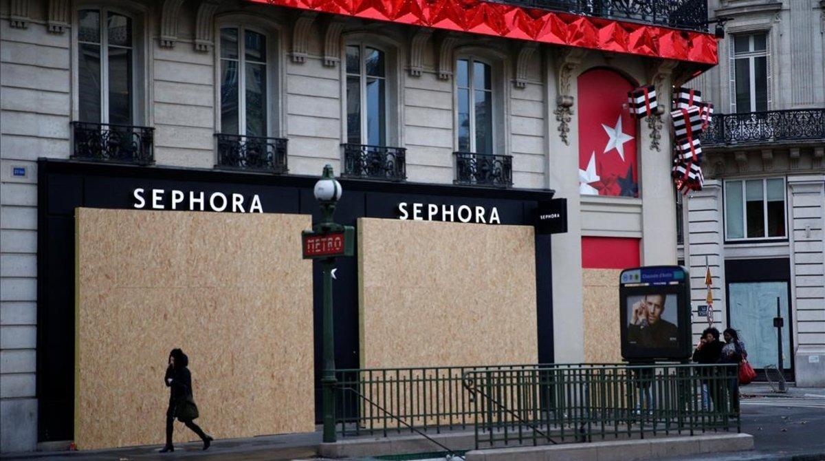 zentauroepp46177215 a woman walks past a closed shop protected by wood panels ne181208092215