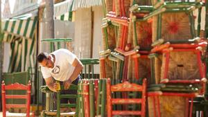 Un trabajador pone a punto las sillas de una caseta de la Feria de Sevilla, en una edición anterior a la expansión del coronavirus. 