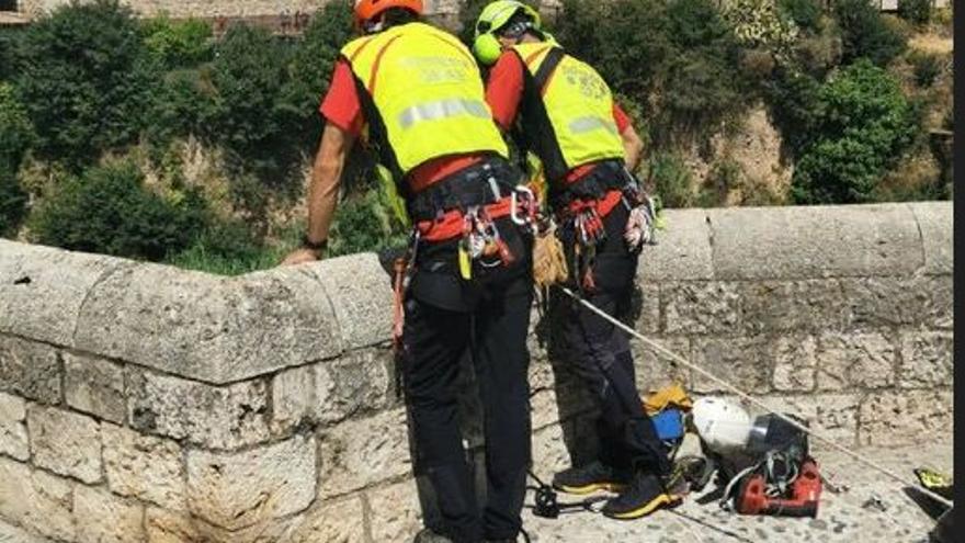 Dos bombers durant el rescat al pont vell de Besalú.