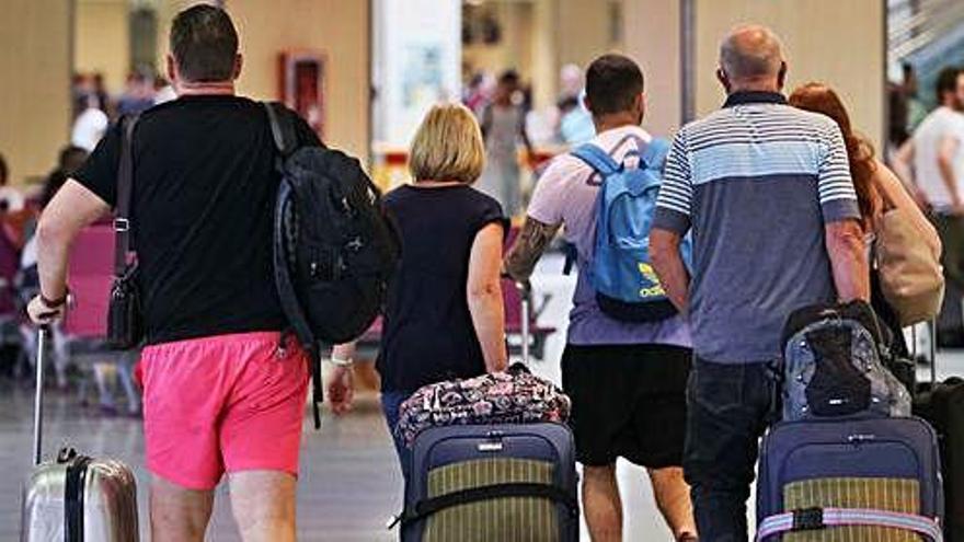 Un grupo de turistas arrastra sus maletas en el interior de la terminal del aeropuerto de Ibiza.