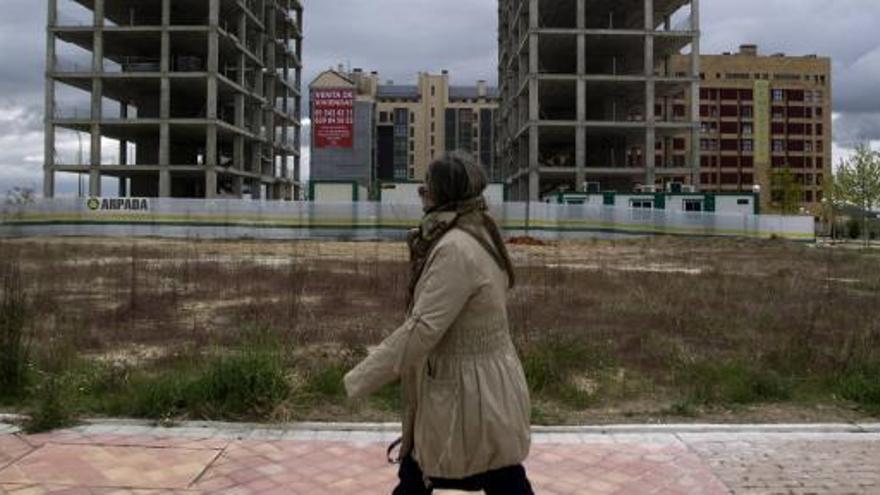 Una mujer pasea ante construcciones paradas.