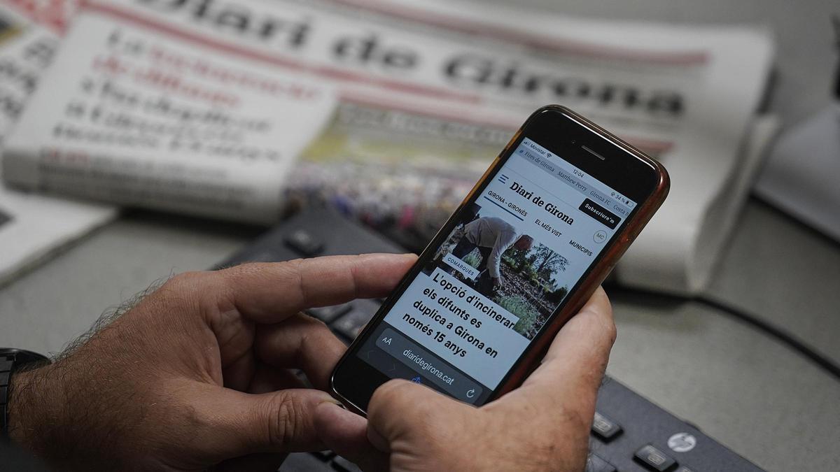 Un lector consulta l'edició digital de Diari de Girona en el seu telèfon mòbil.