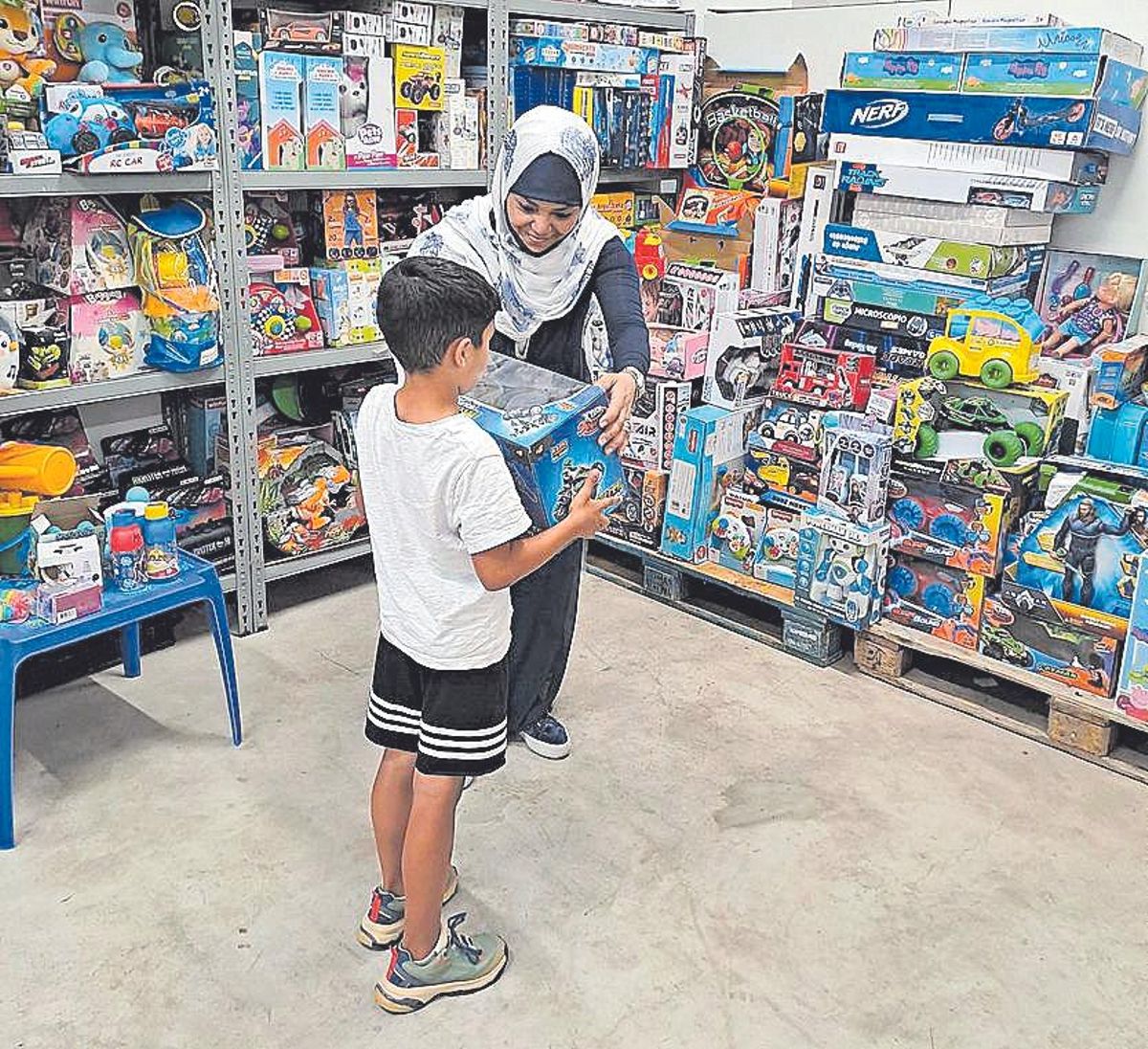 Una de las voluntarias de Mensajeros de la Paz en Castelló entrega un juguete a un niño, gracias a la ayuda de Todojuguete.
