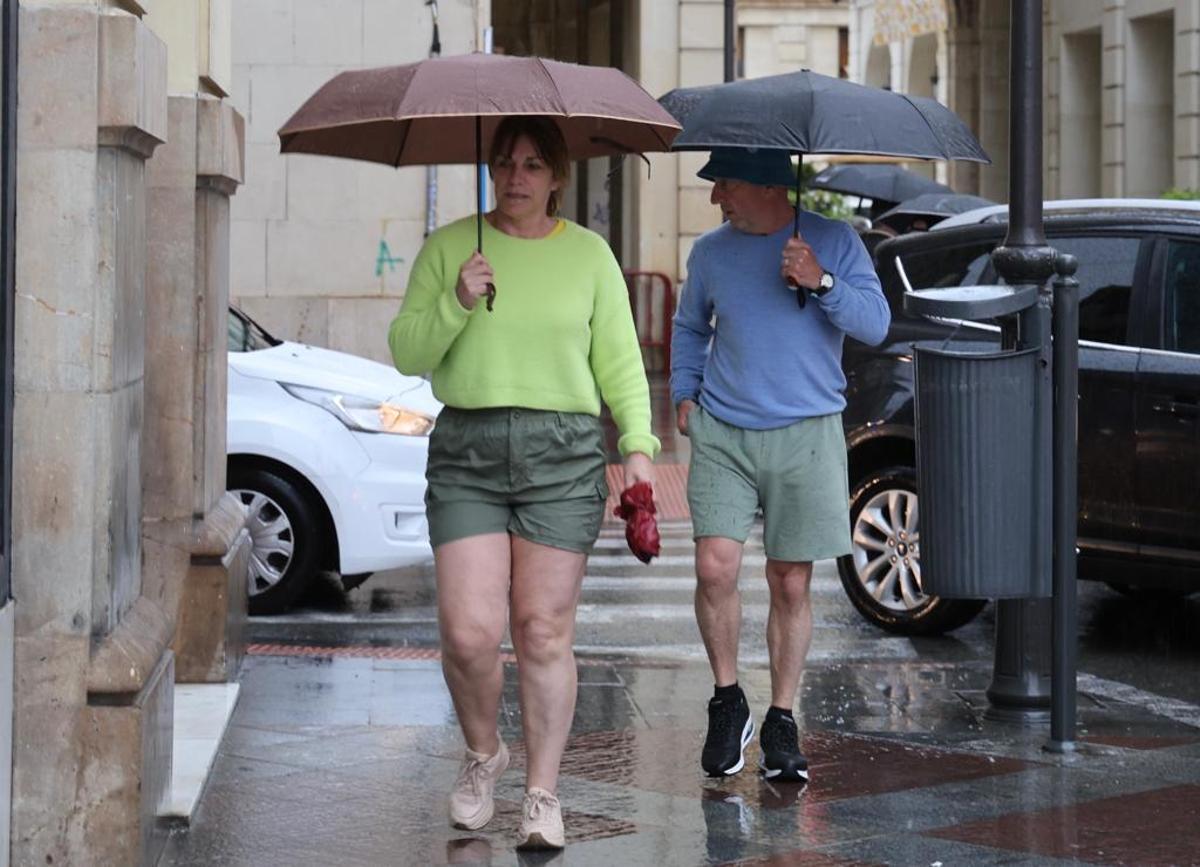 Dos turistas pasean por el centro de Alicante este martes pese a la lluvia.