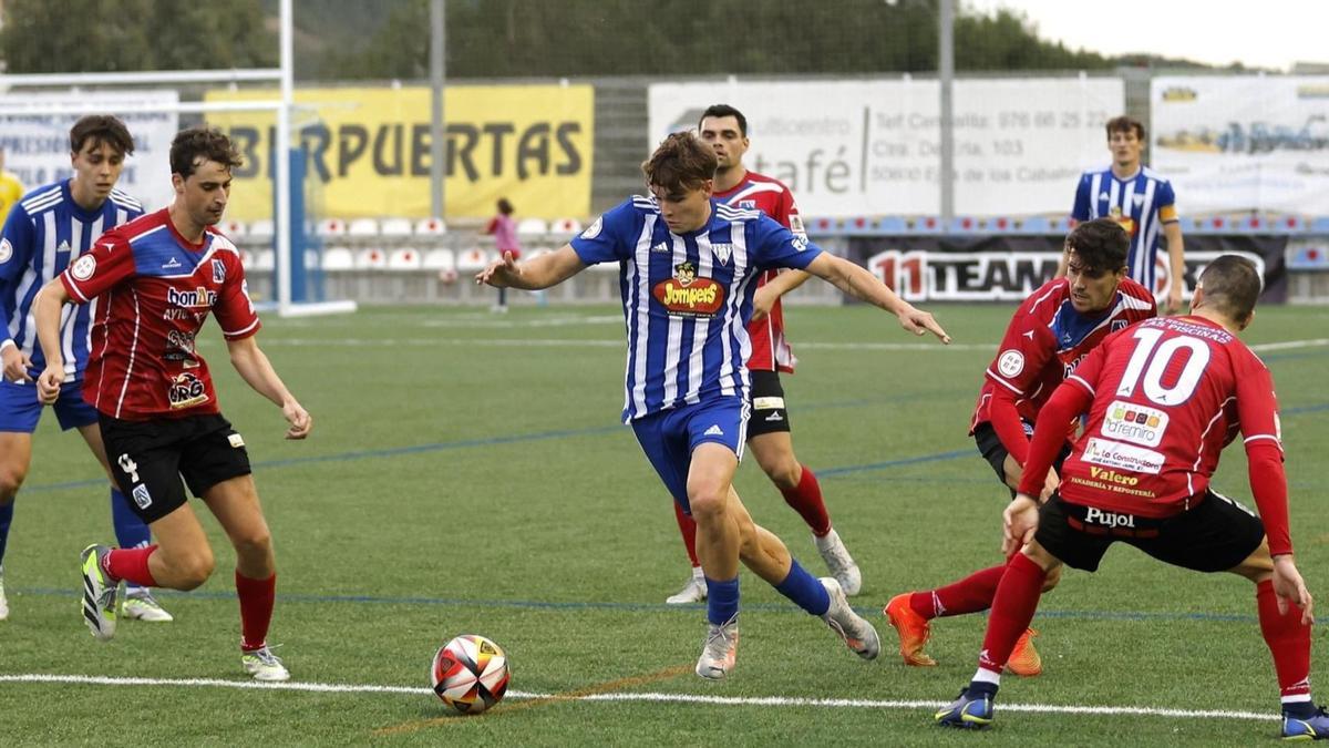 Un futbolista de la SD Ejea trata de avanzar con el balón en presencia de varios jugadores rivales en un encuentro de su equipo.