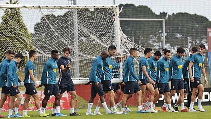 Los jugadores del Sporting trasladan una de las porterías en el campo número 2 de Mareo junto al preparador físico Fran Albert.