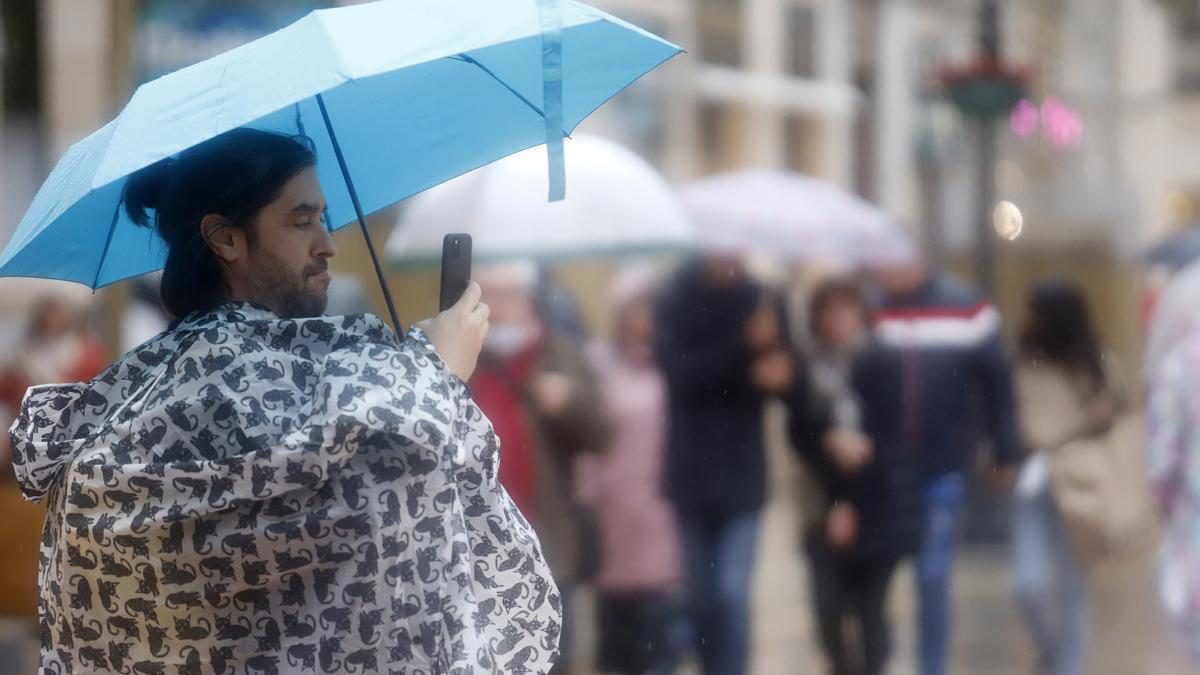 La gente se protege de la fuerte lluvia en Málaga.