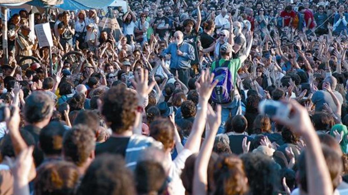 Arcadi Oliveres, presidente de la asociación Justícia i Pau (en el centro de la imagen), se dirige, micrófono en mano, a los concentrados, ayer en la plaza de Catalunya de Barcelona.