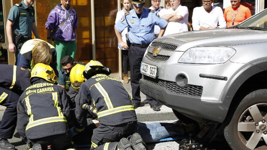 Los bomberos tratan de rescatar a la mujer de los bajos del coche.