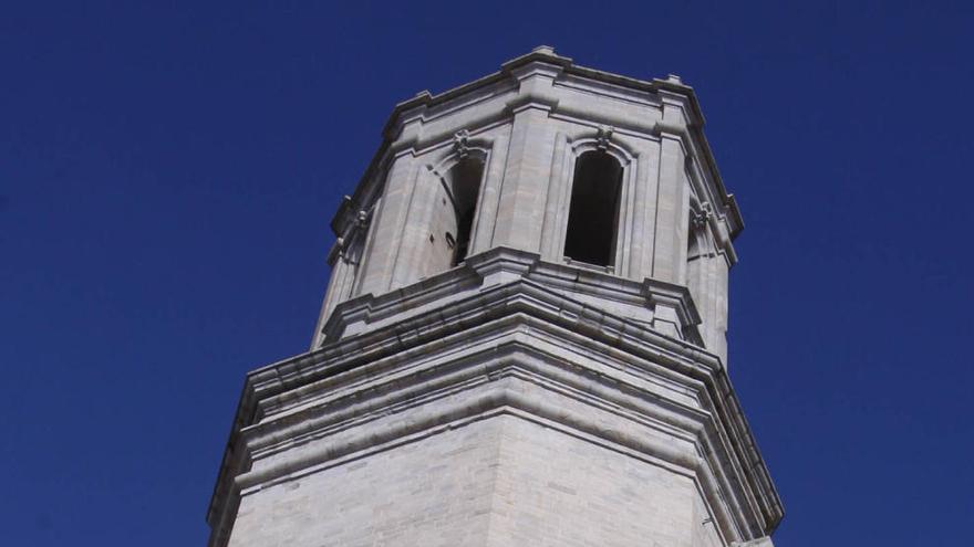 Un grup de persones al peu de la torre del campanar de la Catedral de Girona, on hi ha el rellotge del temple · Marc Martí