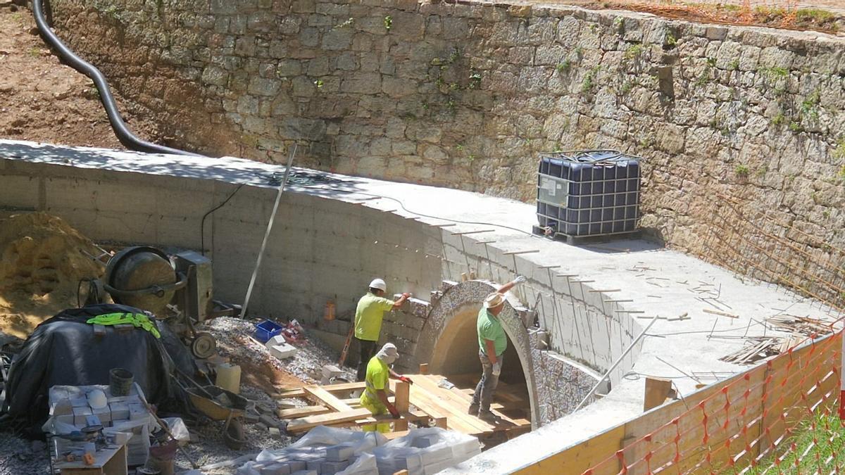 Operarios colocando piedra este jueves en la estructura de hormigón del puente de la nueva senda.