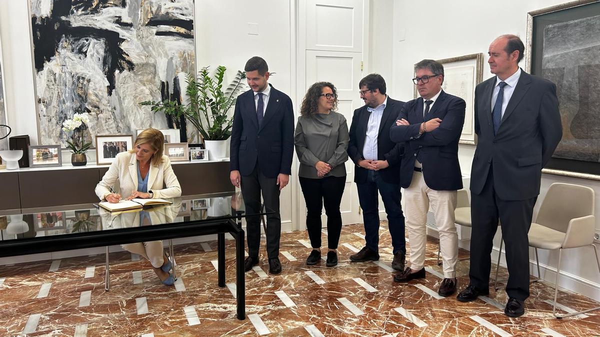 La consellera Salomé Pradas, firma en el libro de honor de Gandia. A su lado, el alcalde y los portavoces de todos los grupos políticos municipales.