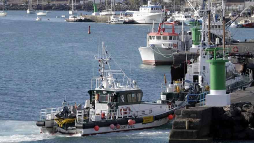 El cadáver de uno de los ocho inmigrantes desparecidos hoy tras el vuelco de una patera en aguas de Lanzarote, es desembarcado en el puerto Naos de Arrecife tras ser rescatado por una patrullera de la Guardia Civil.