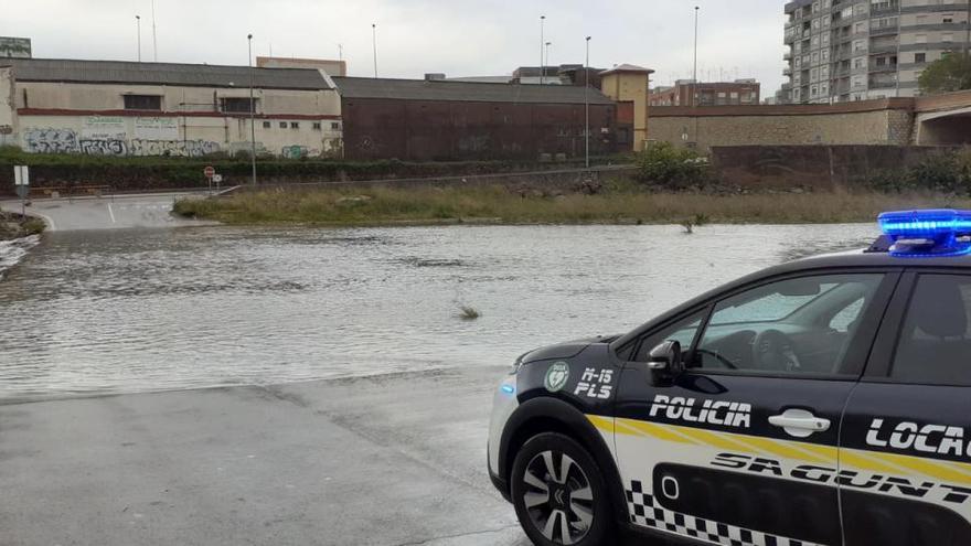 Un coche de policía, ante el río cortado.