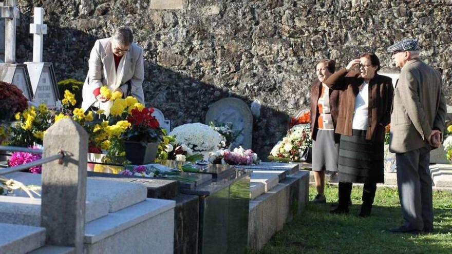 Una vecina arregla un centro de flores en el cementerio de Silleda. // Bernabé/Gutier