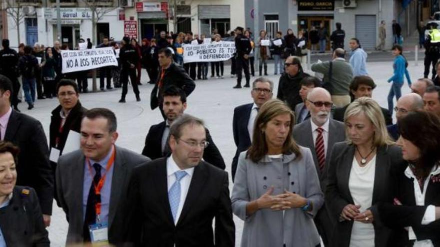 Ana Mato, junto a Luis Rosado y Sonia Castedo, a su llegada al ADDA con los manifestantes al fondo.