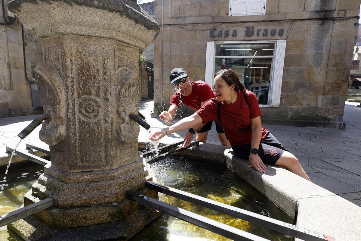 Dos peregrinos utilizan la Fonte dos Tornos, en la calle Real.