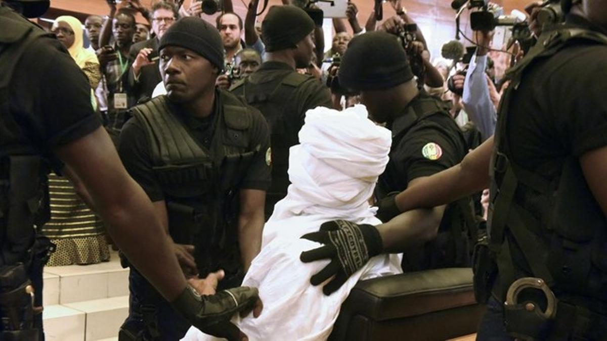 Habré, completamente tapado con una vestimenta blanca, rodeado de policías en el tribunal, en Dakar, este lunes.