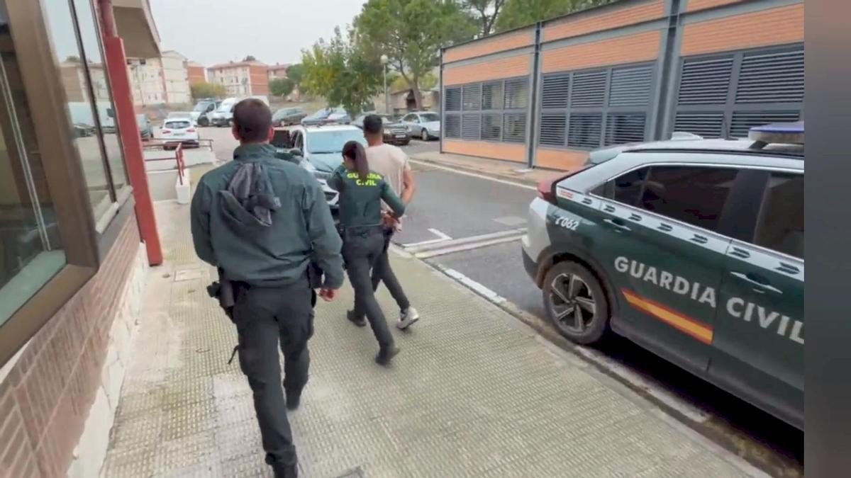 Dos agentes guardia civil llevan esposado detenido control carretera