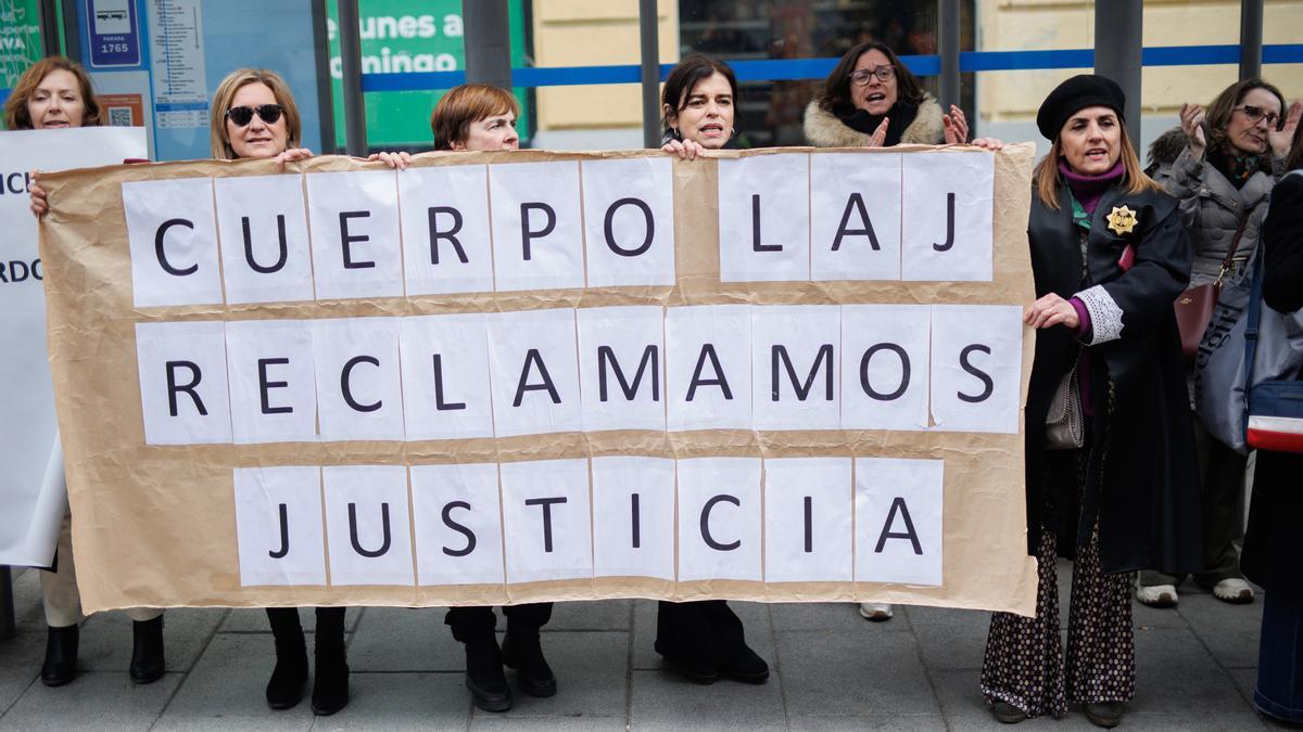 Varias mujeres sujetan una pancarta de &#039;Cuerpo Laj, reclamamos justicia&#039; a las de la sede del Ministerio donde se reúnen el comité de huelga de los Letrados de Justicia y el Ministerio, a 27 de febrero de 2023, en Madrid.