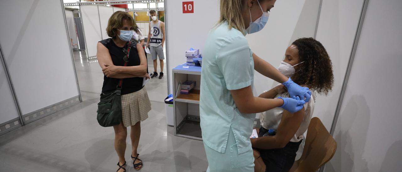 Una joven se   vacuna en IFA bajo  la atenta mirada de su madre.