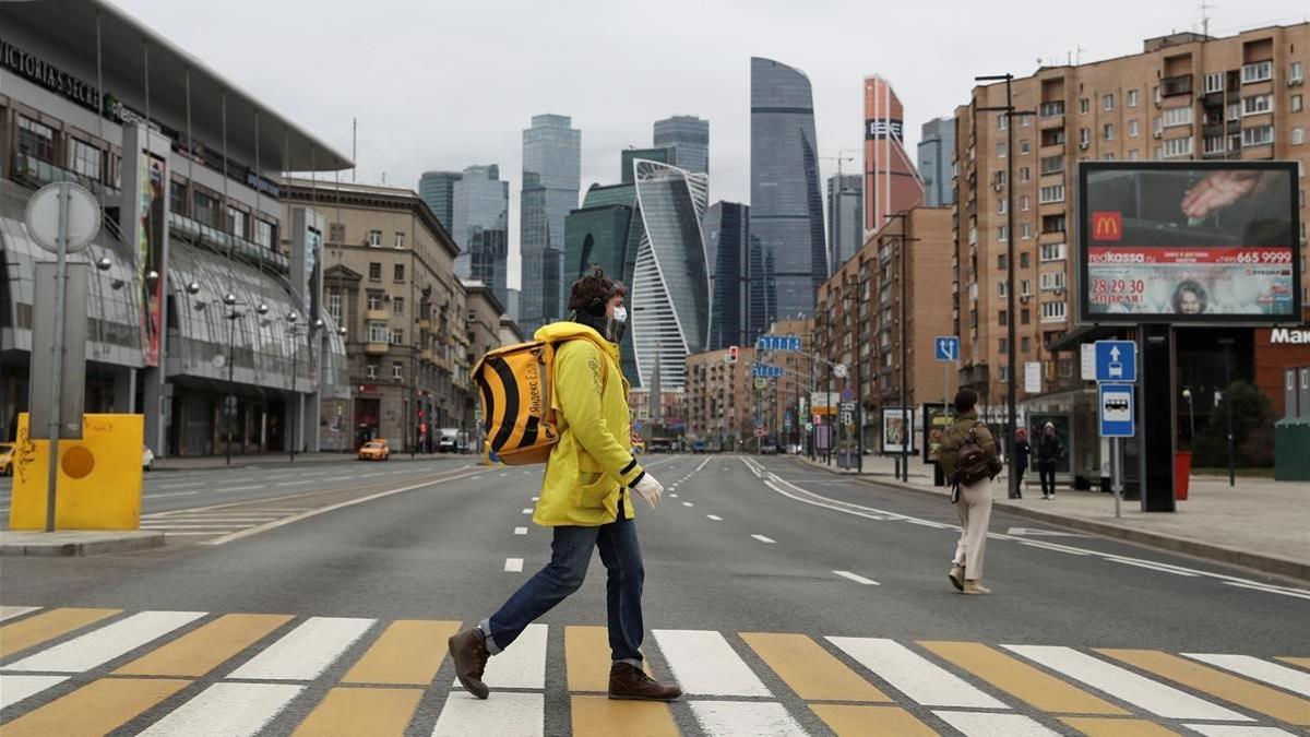 Un repartidor de comida a domicilio cruza una desierta calle de Moscú, este lunes.