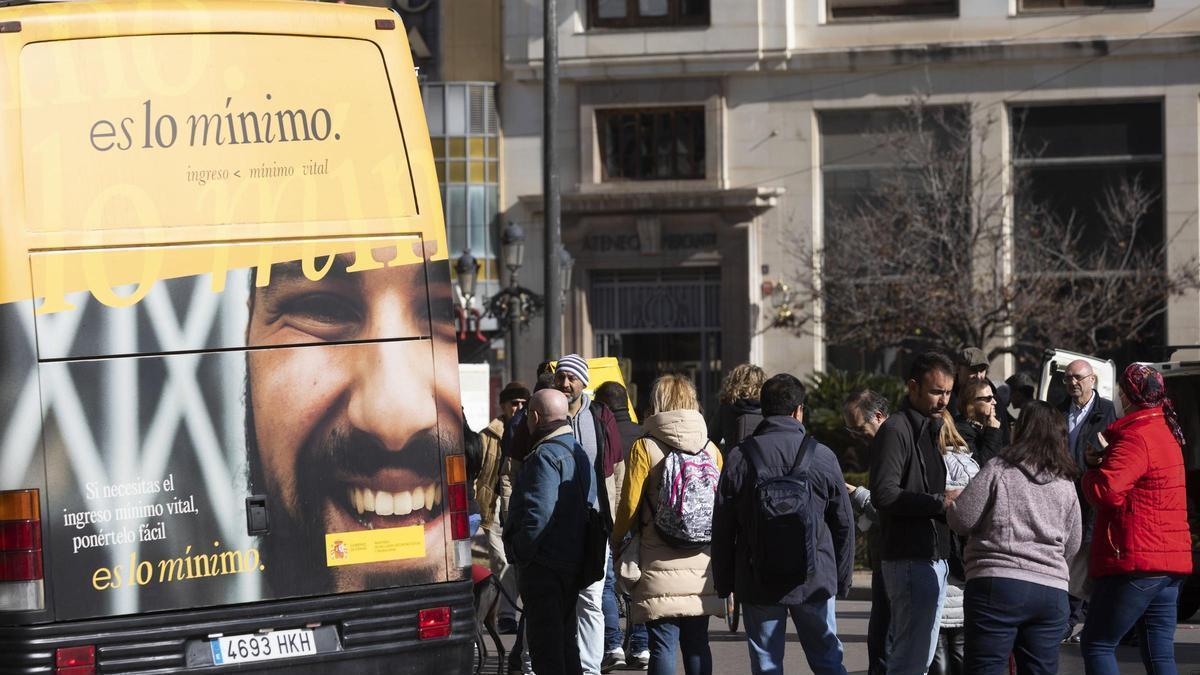 Un grupo de personas espera su turno para solicitar datos sobre el Ingreso Mínimo Vital en un autobús informativo.