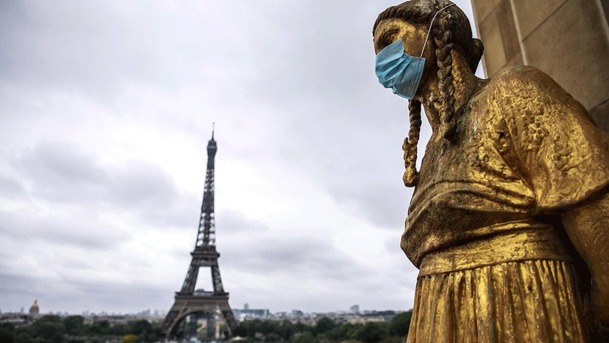 Una de las estatuas de los jardines del Trocadero, ataviada con una mascarilla, con la Torre Eiffel al fondo, el 3 de mayo