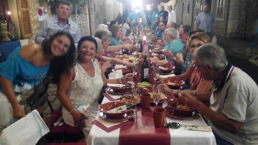 Un grupo de comensales cena en una de las calles del pueblo.