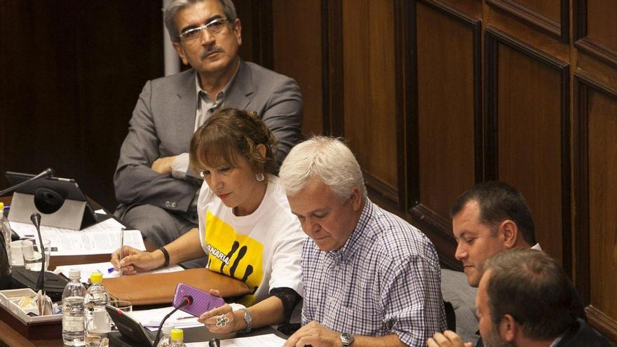 Carmelo Ramírez revisa un documento con Román Rodríguez al fondo.