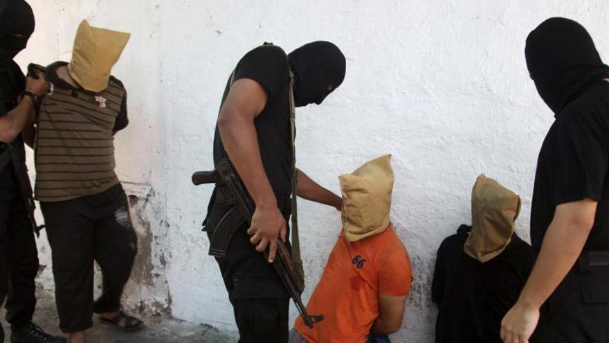 Miembros de Hamás con uno de los ejecutados.