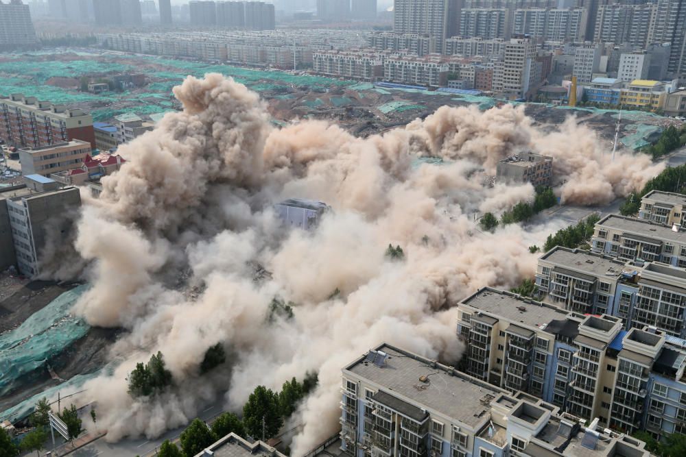 Buildings crumble during a controlled demolition ...