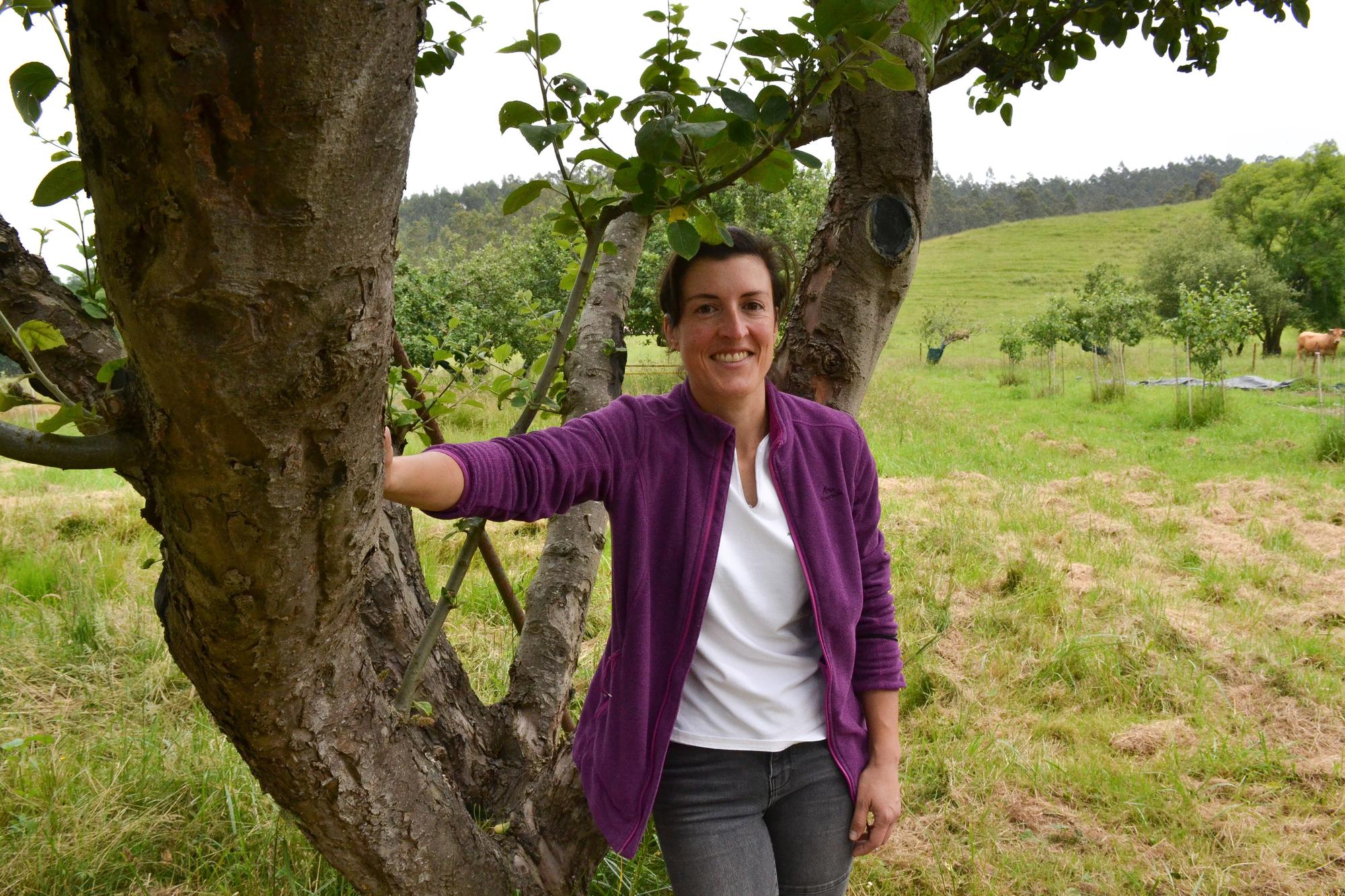 Cristina Secades, apoyada en el tronco de uno de sus manzanos.