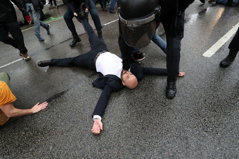 Un manifestante es tumbado por  un agente policial.