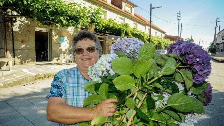 Una vecina con hortensias ante el bar donde desayunó Rajoy. // I.A.