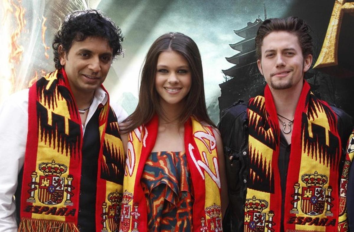 M. Night Shyamalan, a l’esquerra, amb els actors Nicola Peltz i Jackson Rathbone, guarnits amb bufandes de ’la Roja’ , avui, a Madrid.