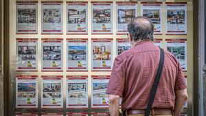 Un hombre contempla ofertas de vivienda en el escaparate de una inmobiliaria.