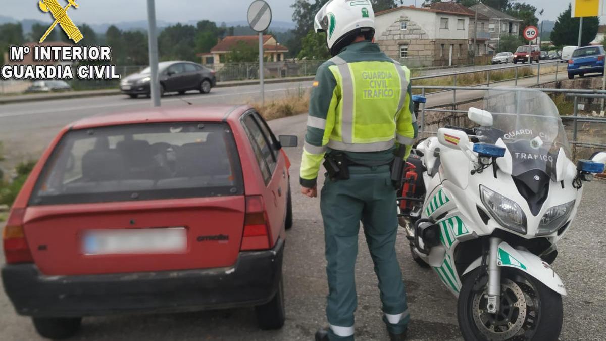 Un motorista de Tráfico junto al coche del conductor que viajó a Ourense sin carné.