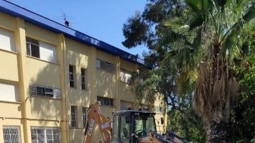 Una máquina trabajando ante el edificio del colegio.