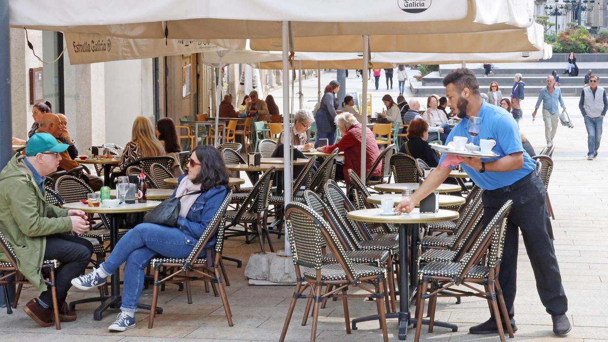 Un camarero limpiando la mesa de una terraza en un bar de Vigo.