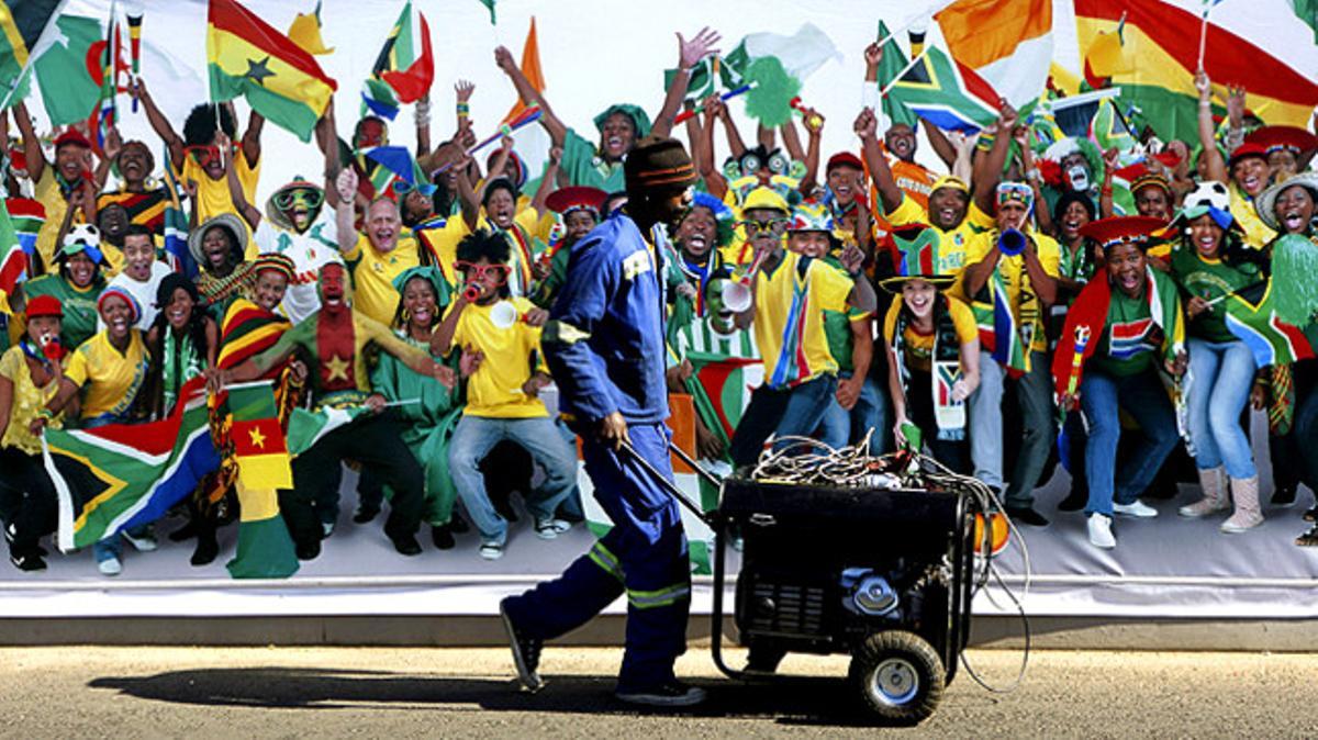 Un treballador passa pel costat d’un cartell de la Copa del Món, l’esdeveniment esportiu més vist del planeta.