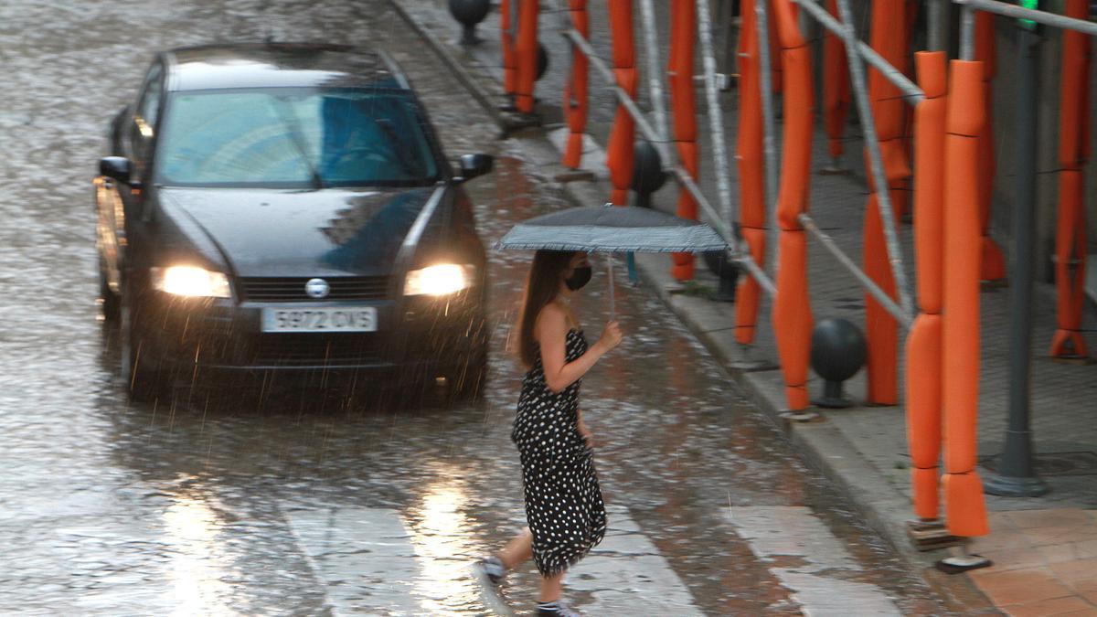 Una mujer cruza un paso de cebra bajo la tormenta, este martes en Ourense.