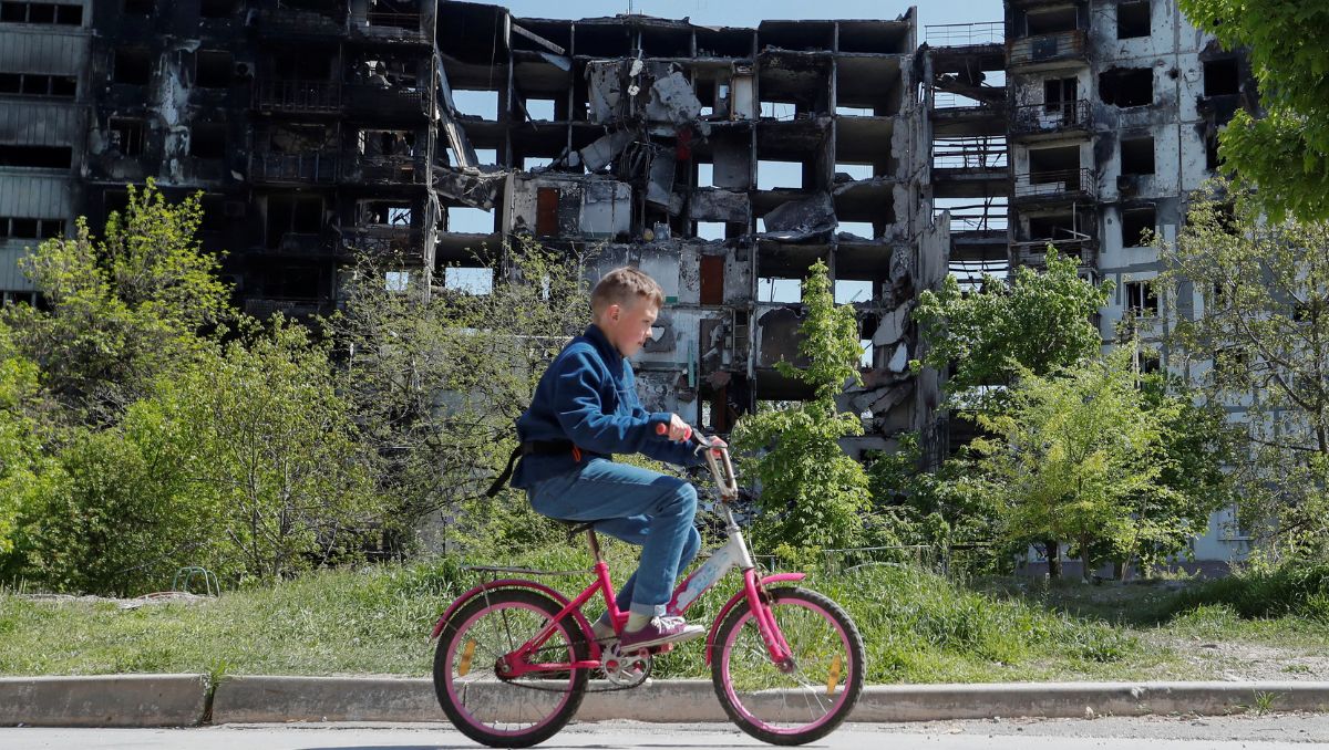 Un niño en bicicleta alrededor de un edificio destruido en Mariúpol, a principios de mayo.