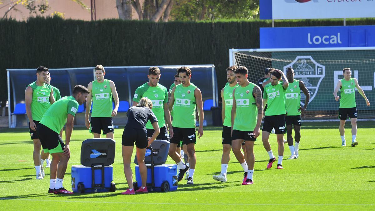 Los jugadores del Elche, ayer, hidratándose en el entrenamiento, junto a la nutricionista.