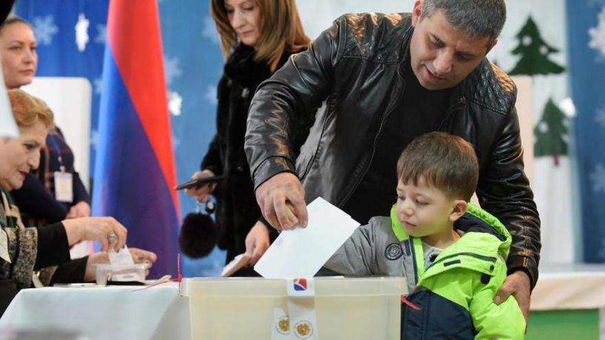 Un hombre vota con su hijo en Armenia.