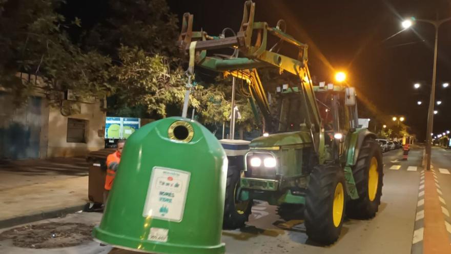 Un tractor levanta uno de los contenedores de reciclaje de residuos que hay distribuidos por el municipio costero. | BELLIDO