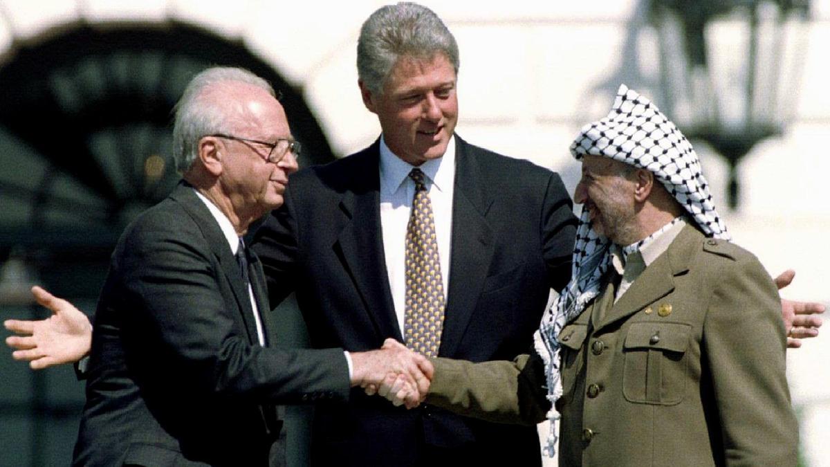 El primer ministro israelí, Yitzhak Rabin, y el líder de la Organización para la Liberación de Palestina, Yasir Arafat, estrechan sus manos ante el presidente de EEUU, Bill Clinton, el 13 de septiembre de 1993 en la Casa Blanca.