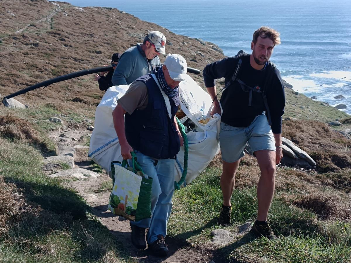 Voluntarios portando un saco de lixo mariño retirado en Touriñán.
